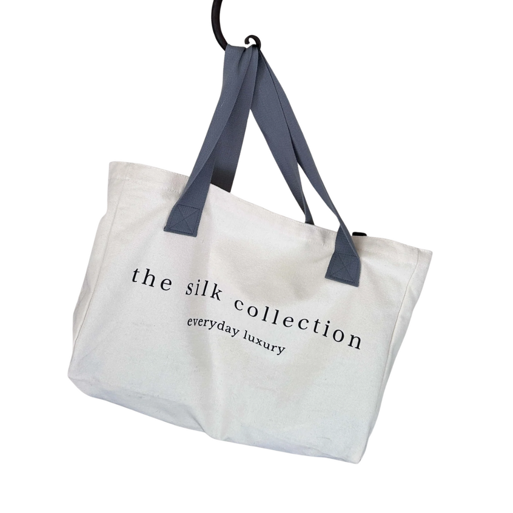 Large canvas tote bag with navy blue handles printed with The Silk Collection logo