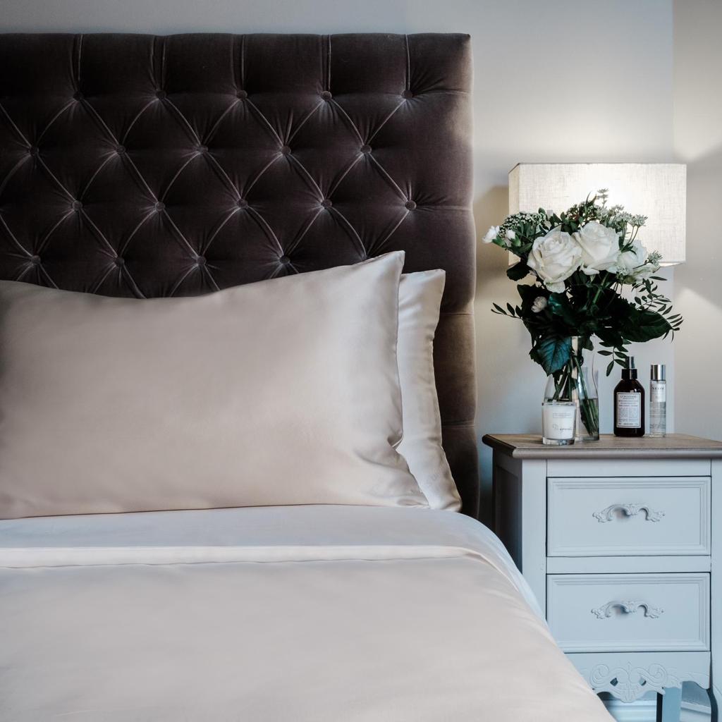 Oyster grey mulberry silk pillowcases on a velvet headboard in a bedroom setting