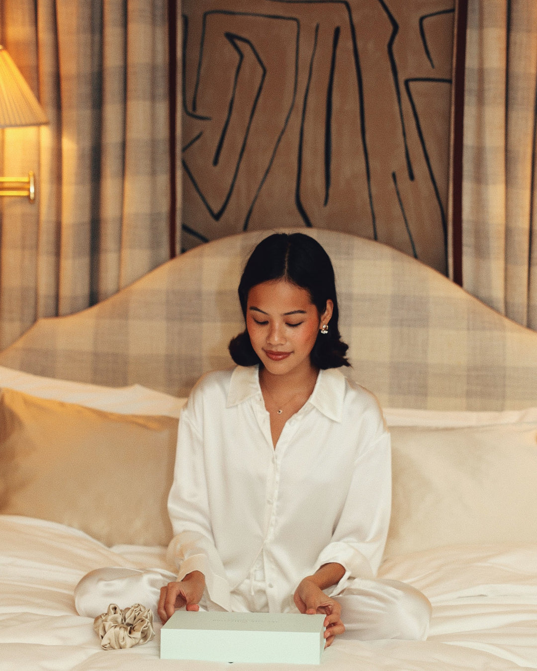 Pearl white silk pyjama set opening gift box on bed