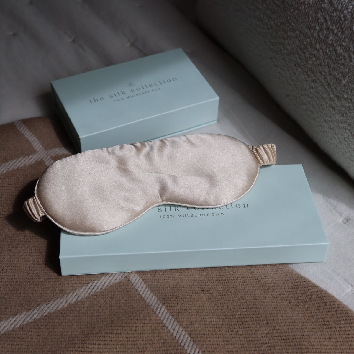 Pearl white mulberry silk eye mask resting on The Silk Collection gift box