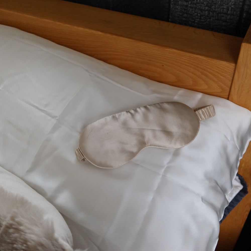 Champagne silk eye mask resting on a mulberry silk pillowcase, ready for the night